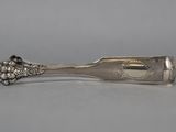 a close up of a silver spoon with a flower on it