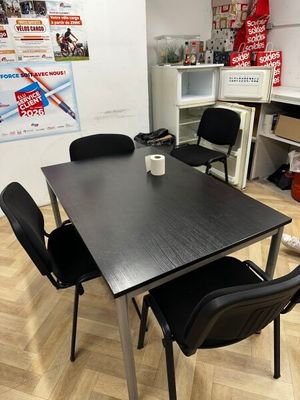 une table noire avec quatre chaises et une tasse de café posée dessus