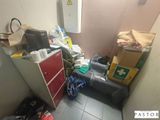 une petite pièce avec un réfrigérateur et plein de choses par terre