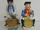 two figurines of a man and a woman sitting on a barrel