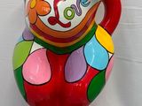 un vase coloré posé sur un socle noir devant un mur blanc