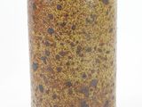 un vase brun et noir posé sur une surface blanche