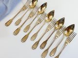 a lot of silver spoons and forks on a white table