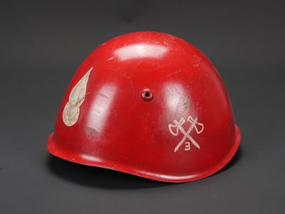 un vieux casque rouge avec un autocollant, posé sur une table