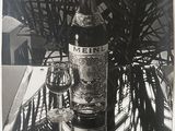 photographie en noir et blanc d'une bouteille de vin posée sur une table à côté d'un palmier