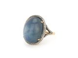 gros plan d'une bague avec une pierre bleue entourée de diamants