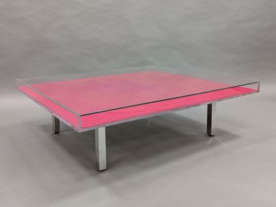 une table basse rose avec un plateau en verre et des pieds en métal