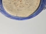 underside view of a blue and white vase on a white surface