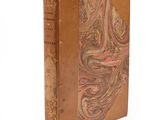 an old book with a brown cover sitting on top of a white surface