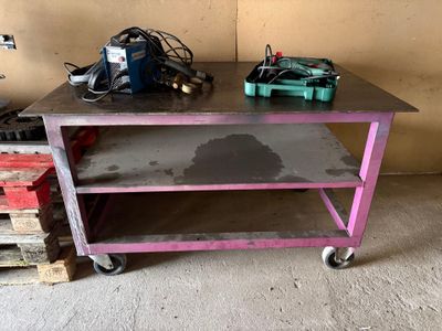 une table en métal sur laquelle se trouve une étagère rose, dans une pièce