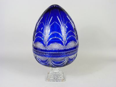 une image représentant un œuf en verre bleu posé sur un socle transparent