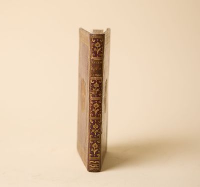un vieux livre posé sur une table à côté d'un mur blanc