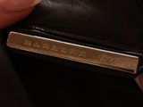 someone is holding a black purse with a name tag on it