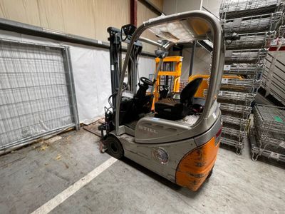 un chariot élévateur dans un entrepôt avec des palettes à l'arrière-plan