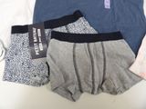 three pairs of men ' s underwear sitting on a bed next to a pair of scissors and a pair of scissors