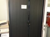 une grande porte métallique sur laquelle est accrochée une pancarte, dans une pièce