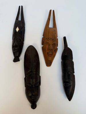 trois masques en bois accrochés les uns à côté des autres sur un mur