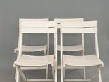 une paire de chaises pliantes blanches adossées à un mur gris
