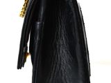 black leather handbag with gold chain strap on a white background