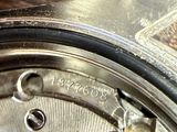 a close up of a silver watch with a brown leather strap