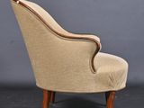 a beige upholstered chair with wooden legs and a curved back