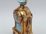 a gold and blue clock with a bird on top of it