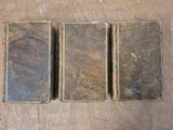 three old books sitting on top of a wooden table next to each other