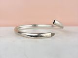 a close up of a silver bang bracelet on a marble surface