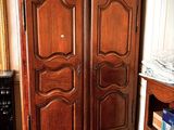 a wooden armoire in a room with a rug on the floor