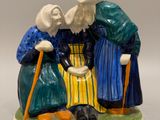 deux figurines représentant des personnes âgées, munies de cannes et coiffées de chapeaux, posées sur une surface blanche