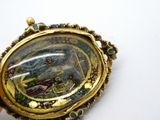 une image représentant une femme dans un bateau, gravée sur une broche en or