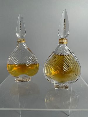 two bottles of perfume sitting on a clear shelf