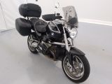 a black motorcycle parked in a room with a white wall