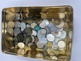 un récipient métallique rempli de pièces de monnaie posé sur une surface blanche