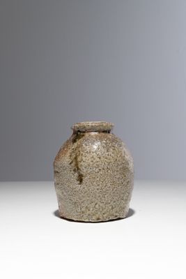 un petit vase posé sur une table, sur fond gris