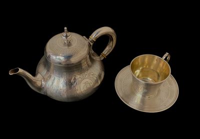 une théière en argent et une tasse en argent sur fond noir
