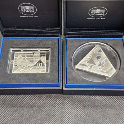 deux pièces d'argent dans une boîte noire posée sur une surface grise