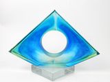 une sculpture en verre bleu percée d'un trou circulaire au centre