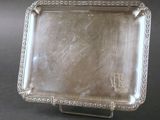 un plat ancien en argent posé sur un socle, sur fond noir