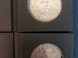 two silver coins are in a black box on a blue cloth