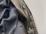 le dos d'une veste noire avec des boutons sur fond blanc