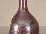 a red vase sitting on a table with a gold top