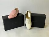 pair of pink and white shoes sitting on top of a black box
