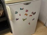 a small white refrigerator with magnets on the door