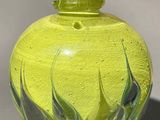 un vase en verre jaune orné d'une fleur bleue
