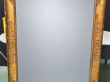a large gold framed mirror with ornate design on a green floor