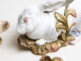 a white rabbit sitting on top of a plate next to a bowl