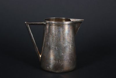 an old silver pitcher on a black background with a black background
