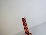 un stylo rouge posé sur un pot à stylos noir
