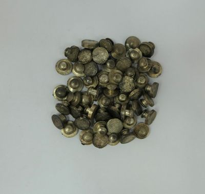 a close up of a pile of metal buttons on a white surface